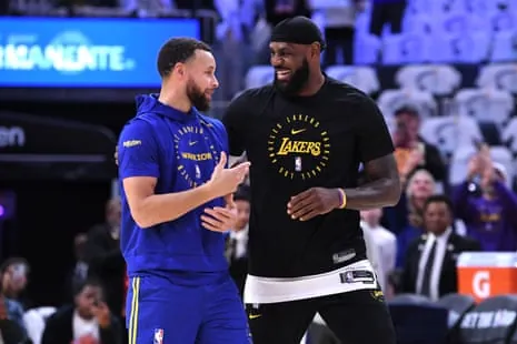 LeBron James and Stephen Curry in Lakers and Warriors warmup gear smile and talk on court