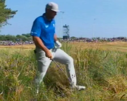 Bryson DeChambeau walks in the long grass by where his ball lies in the rough on the 5th hole.